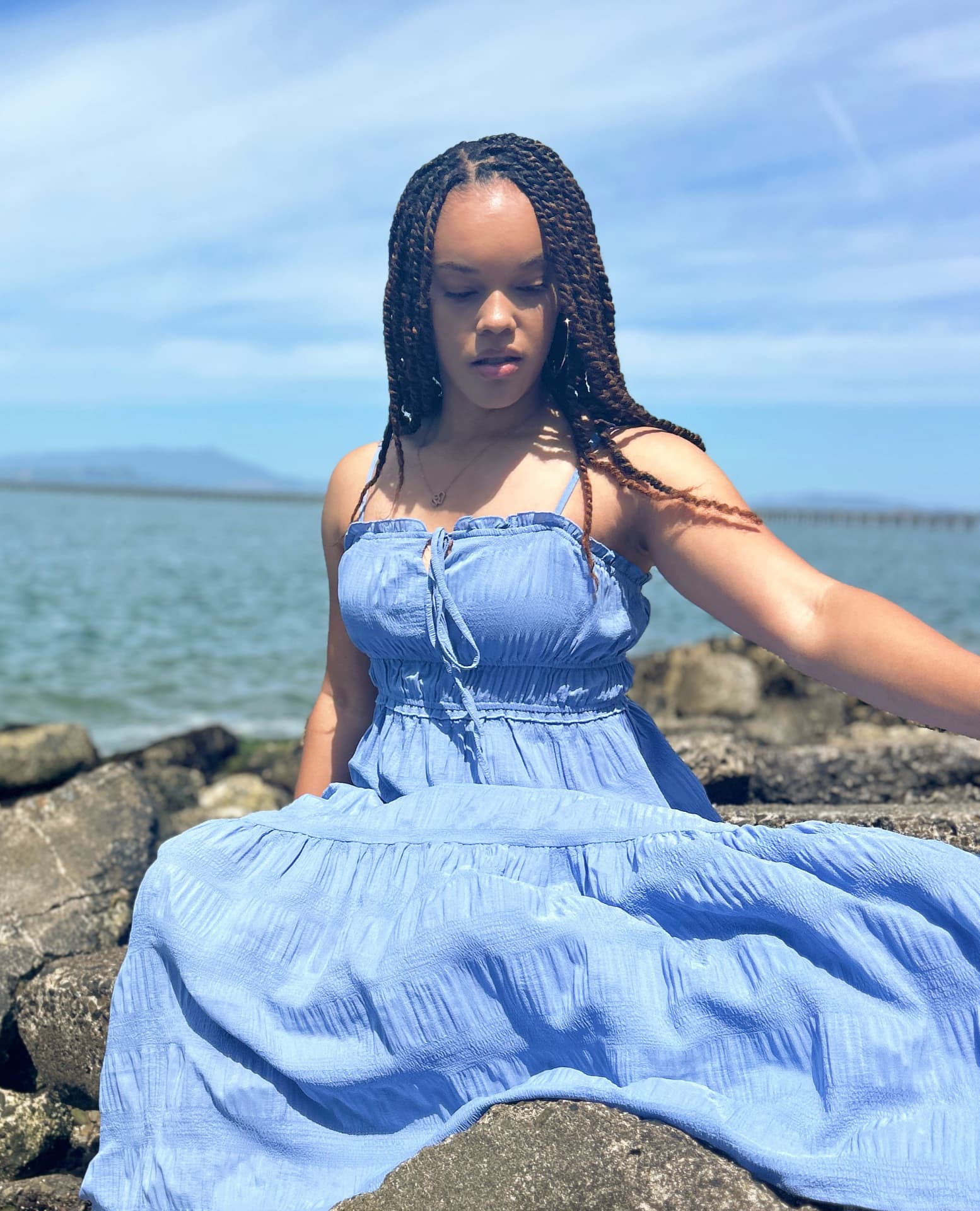 Lisia sitting peacefully by the water in a moment of quiet reflection